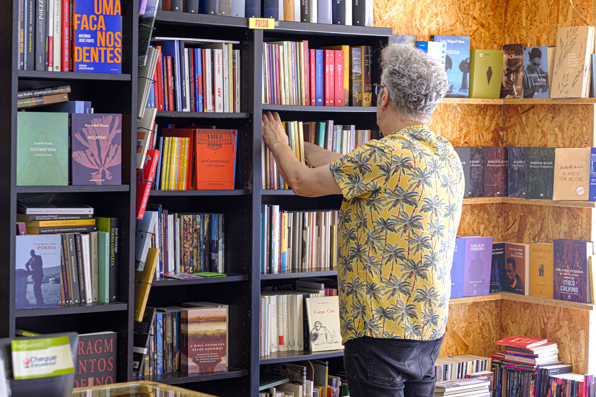 Um homem procura um livre nas estantes da Livraria Tigre de Papoel em Lisboa
